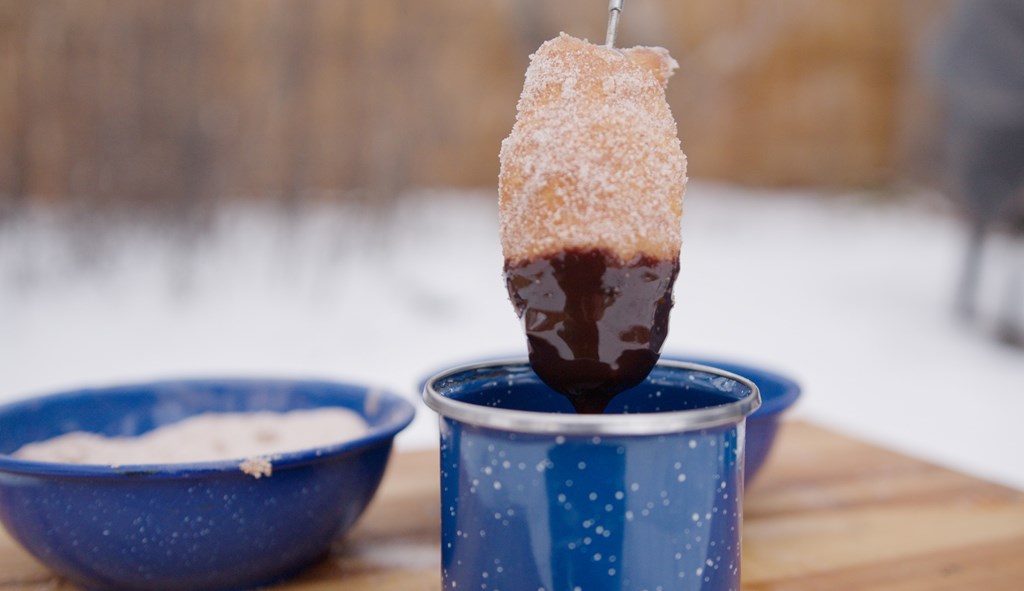 A churro is dipped in chocolate